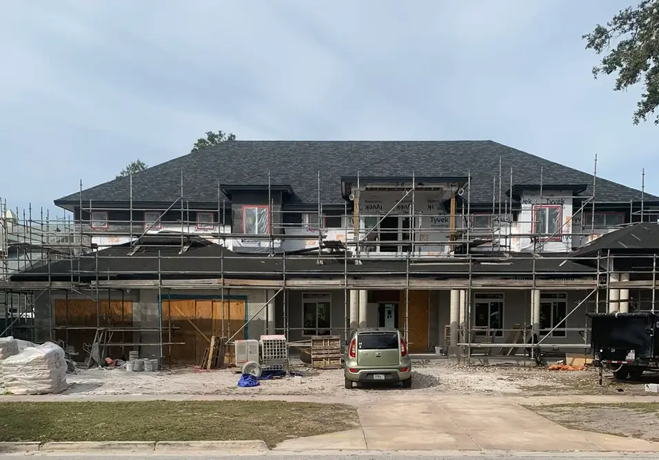 Two-storey house under construction behind scaffolding, new slab and drive in the foreground