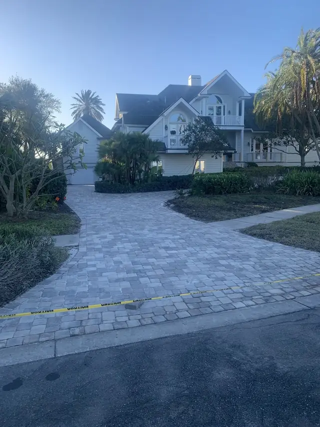 Herringbone paver driveway curving up to a large two-storey Florida house