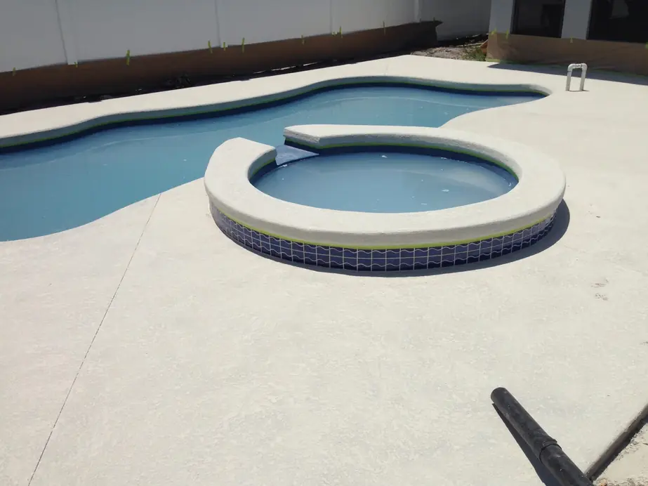 Light knockdown-finish pool deck around a freeform pool and raised round spa